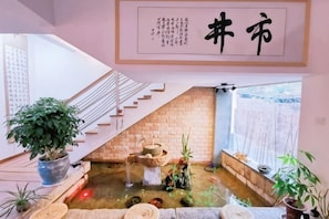 A staircase leading to a room with a view of a koi pond, a brick wall, and a hanging sign with Chinese characters. - Shijing Homestay (Jianshui Ancient City Branch) (Jianshui)