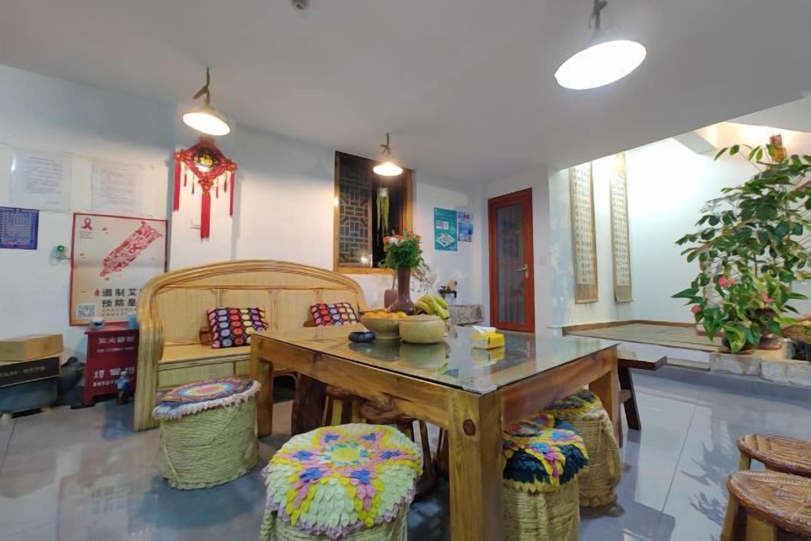 A dining area with a wooden table, woven stools, and a decorative hanging ornament.