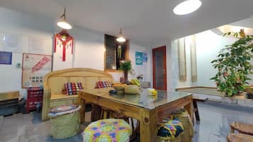 A dining area with a wooden table, woven stools, and a decorative hanging ornament.