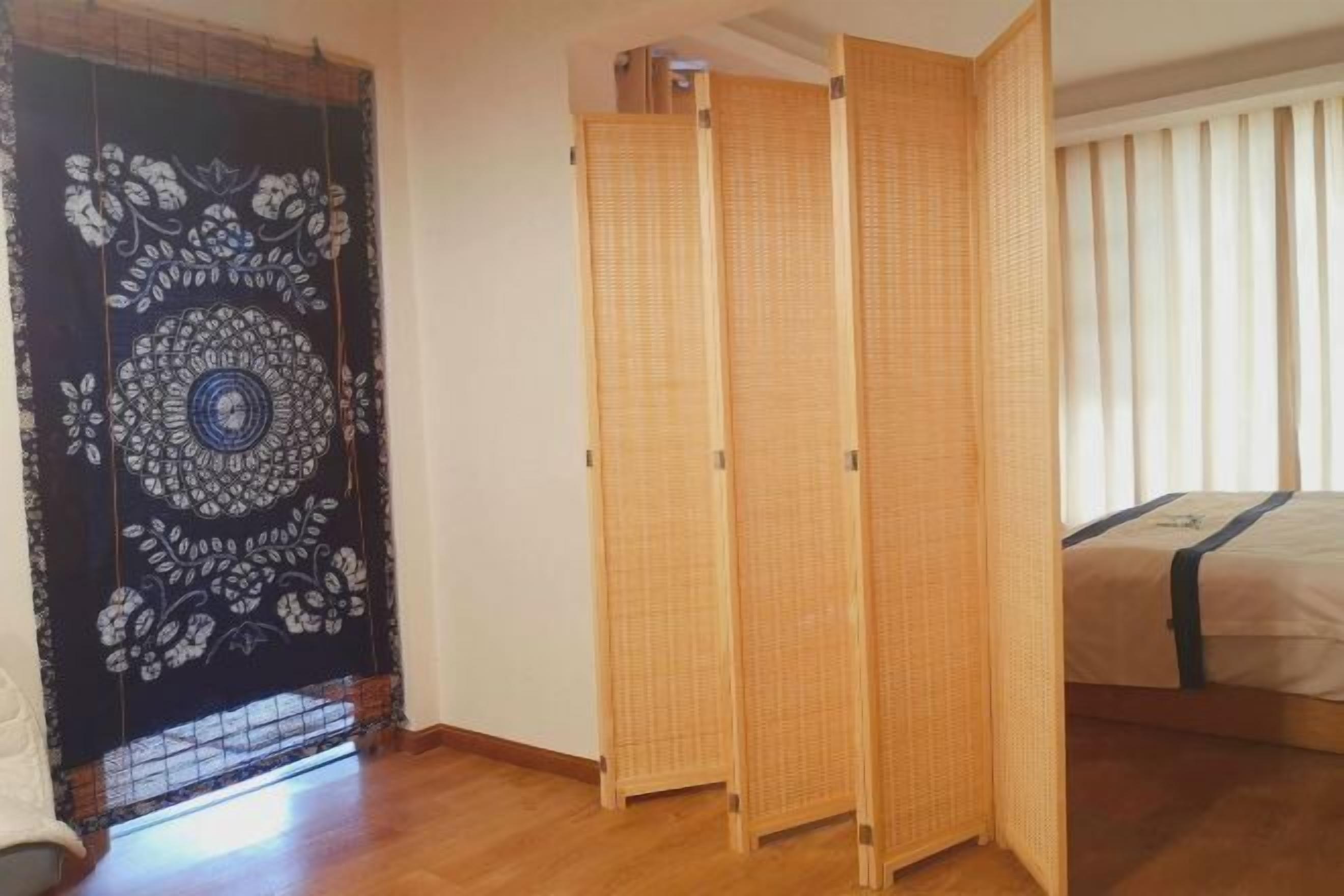 Una habitación con suelo de tatami, cama con detalles azules, un shoji decorado con motivos florales y una puerta corredera.