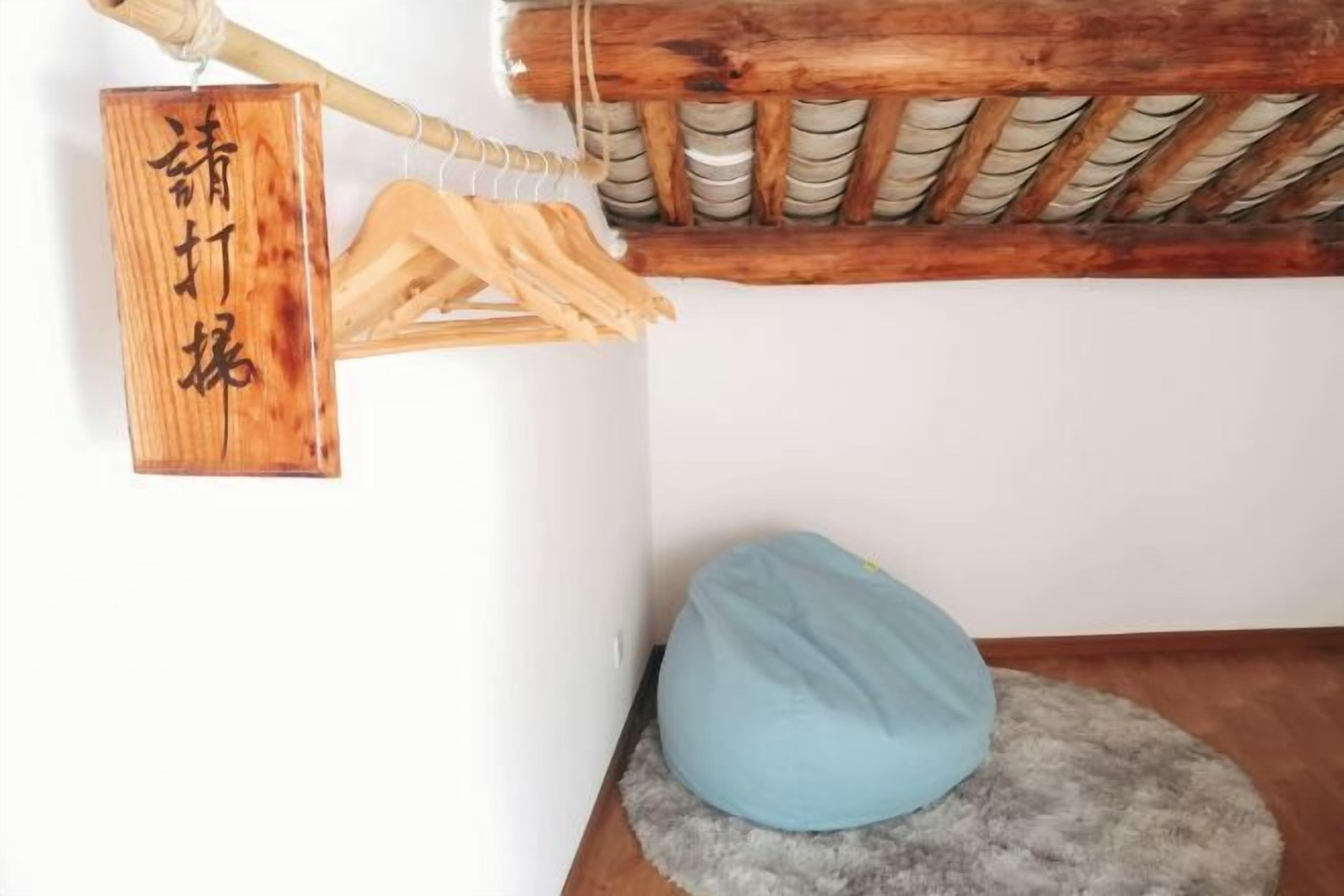 A room with a wooden sign, a blue bean bag chair, and a ceiling with a wooden beam and a woven basket.