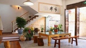 A reception area with a staircase, wooden benches, potted plants, and a table. - Shijing Homestay (Jianshui Ancient City Branch) (Jianshui)