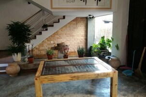 Um quarto com uma mesa de vidro, uma parede de tijolos e uma escada.