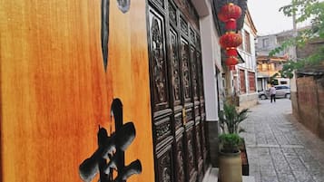 Rua estreita com porta de madeira e decorações tradicionais chinesas.