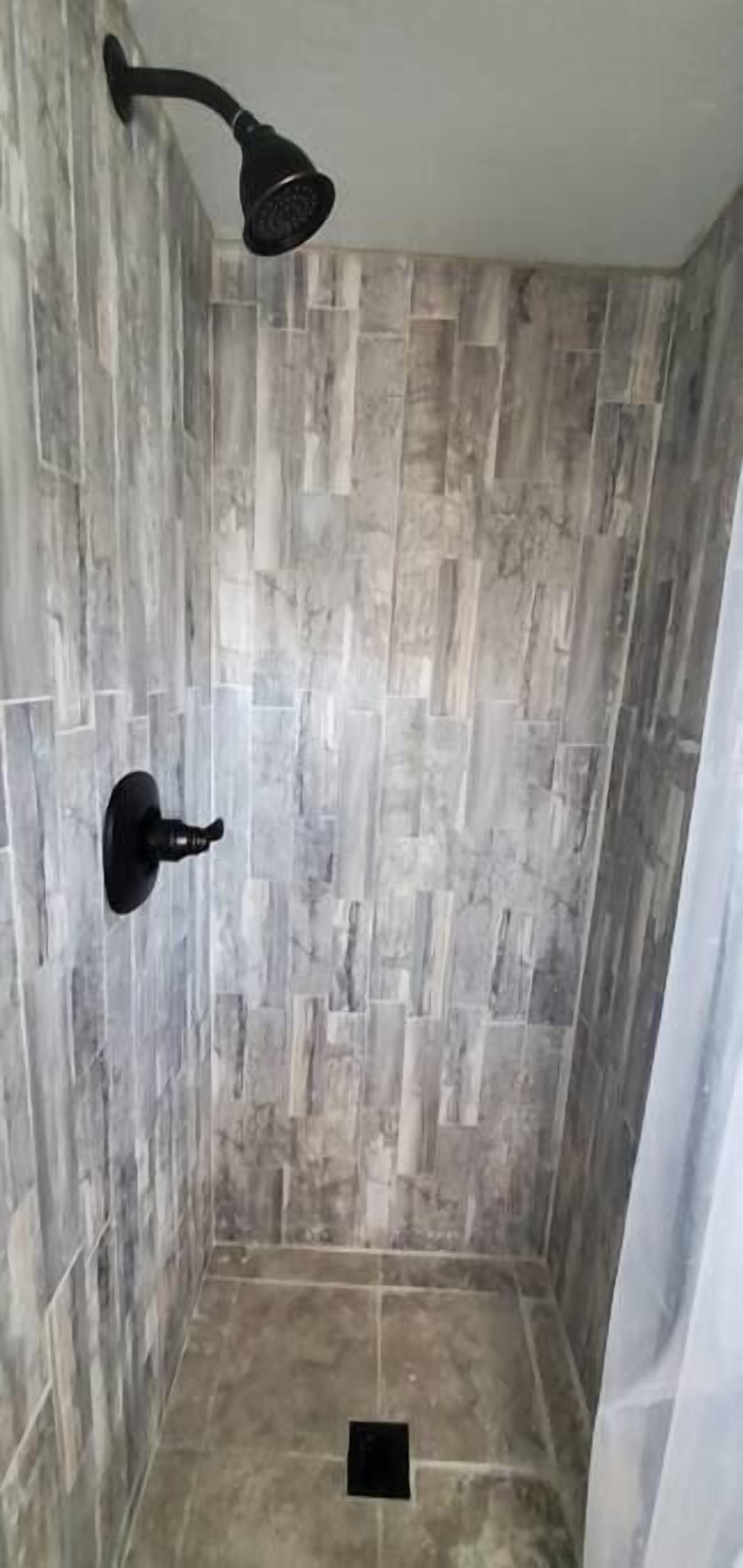 Une douche équipée d’un pommeau de douche fixé au mur et d’un flexible de douche.