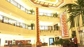 A multi-level hotel lobby with a reception desk, seating areas, and a large decorative wall. - Jinshuiwan Holiday Resort (Shucheng)