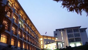 A multi-story hotel with a central courtyard, large windows, and a flag on the roof. - Jinshuiwan Holiday Resort (Shucheng)