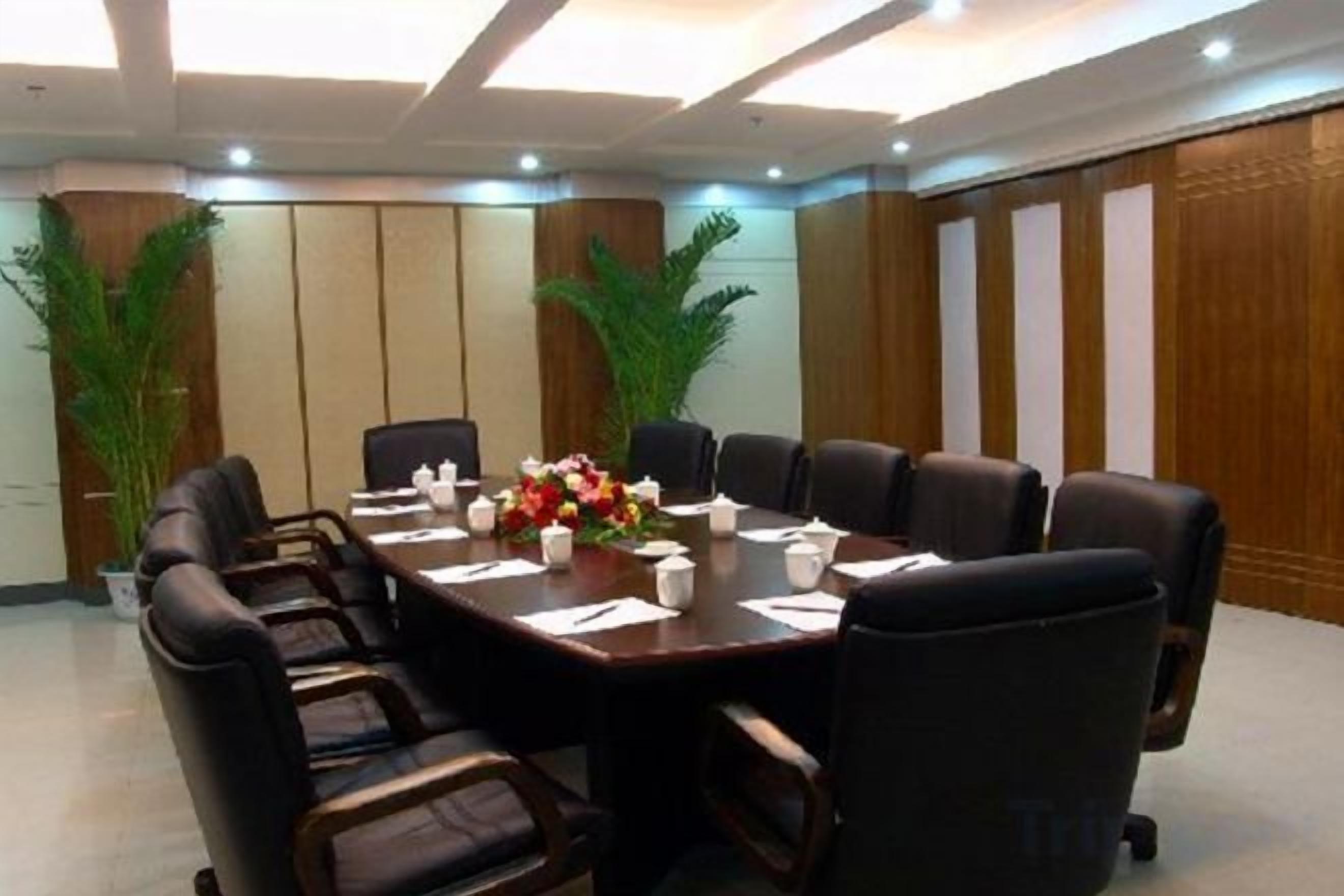 Un salón de conferencias con una larga mesa, varias sillas y un centro de mesa floral.