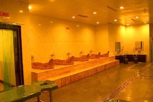 A public restroom with multiple sinks and a long bench.