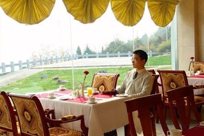 A dining area with a table set for two, chairs, and a view of a park. - Jinshuiwan Holiday Resort (Shucheng)