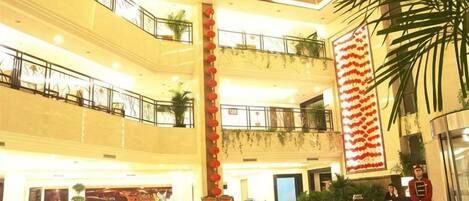 A multi-level hotel lobby with a reception desk, seating areas, and a large decorative wall.