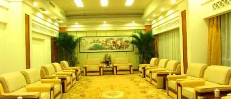 A conference room with a long table and multiple chairs, a patterned carpet, and a painting on the wall.