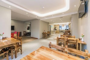A spacious dining area with wooden tables and chairs, a kitchen in the background, and a modern ceiling design. - Superior Hotel (Ziyuan Bus Station) (Ziyuan)