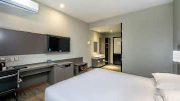 A hotel room with a bed, a desk, a chair, a TV, a mirror, a sink, and a wardrobe.