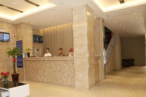 A hotel reception area with a marble reception desk, a TV screen, a staircase, and a potted plant. - Superior Hotel (Ziyuan Bus Station) (Ziyuan)