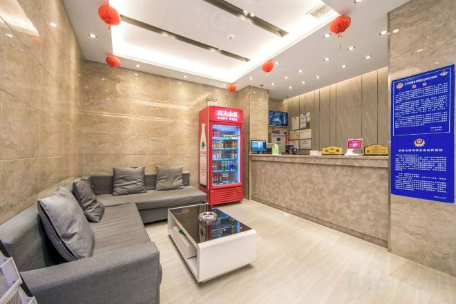 A hotel lobby with a reception desk, a seating area with a sofa, a coffee table, and a vending machine.