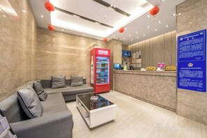 A hotel lobby with a reception desk, a seating area with a sofa, a coffee table, and a vending machine. - Superior Hotel (Ziyuan Bus Station) (Ziyuan)