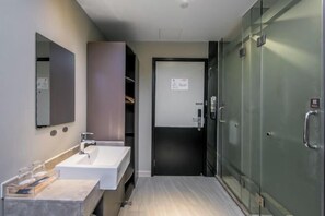 A modern bathroom with a sink, mirror, and glass shower enclosure.
