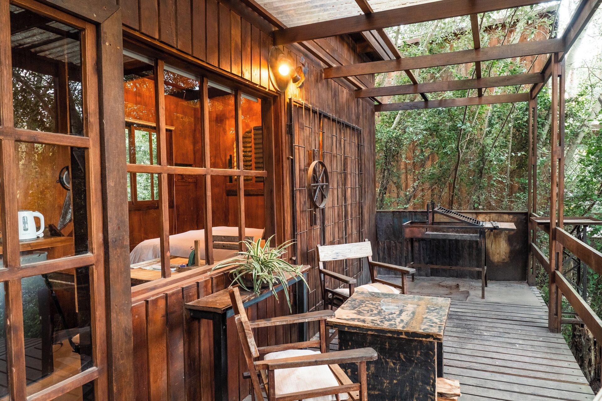 A wooden deck with a table and chairs, a bench, and a fan.