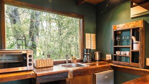 A kitchen with a large window, wooden cabinets, a coffee maker, and a toaster.