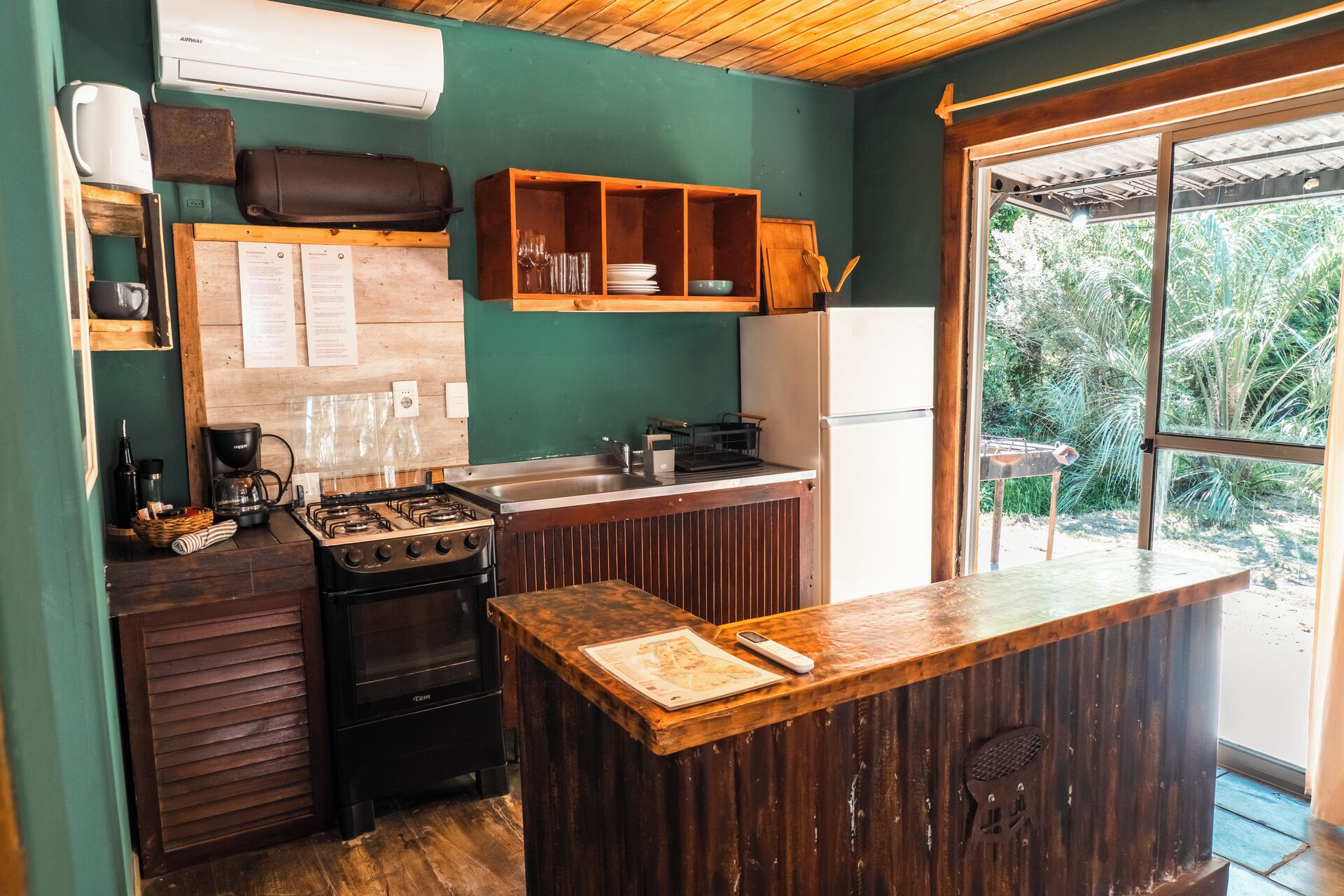 Een compacte keuken met een gasfornuis, een koffiezetapparaat en een houten aanrecht.