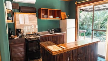 Een compacte keuken met een gasfornuis, een koffiezetapparaat en een houten aanrecht.