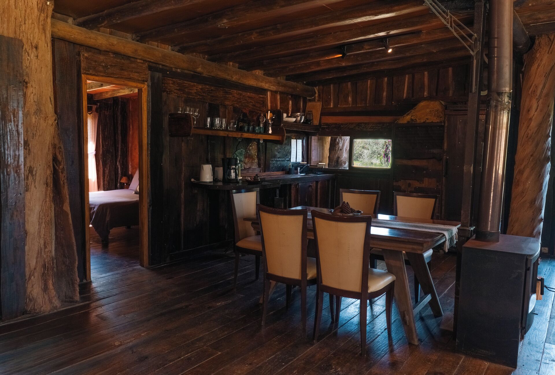 Un interior rústico de madera con barra, sillas de madera y chimenea.