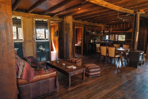 Un intérieur rustique en bois, avec un canapé, un pouf et une table à manger.