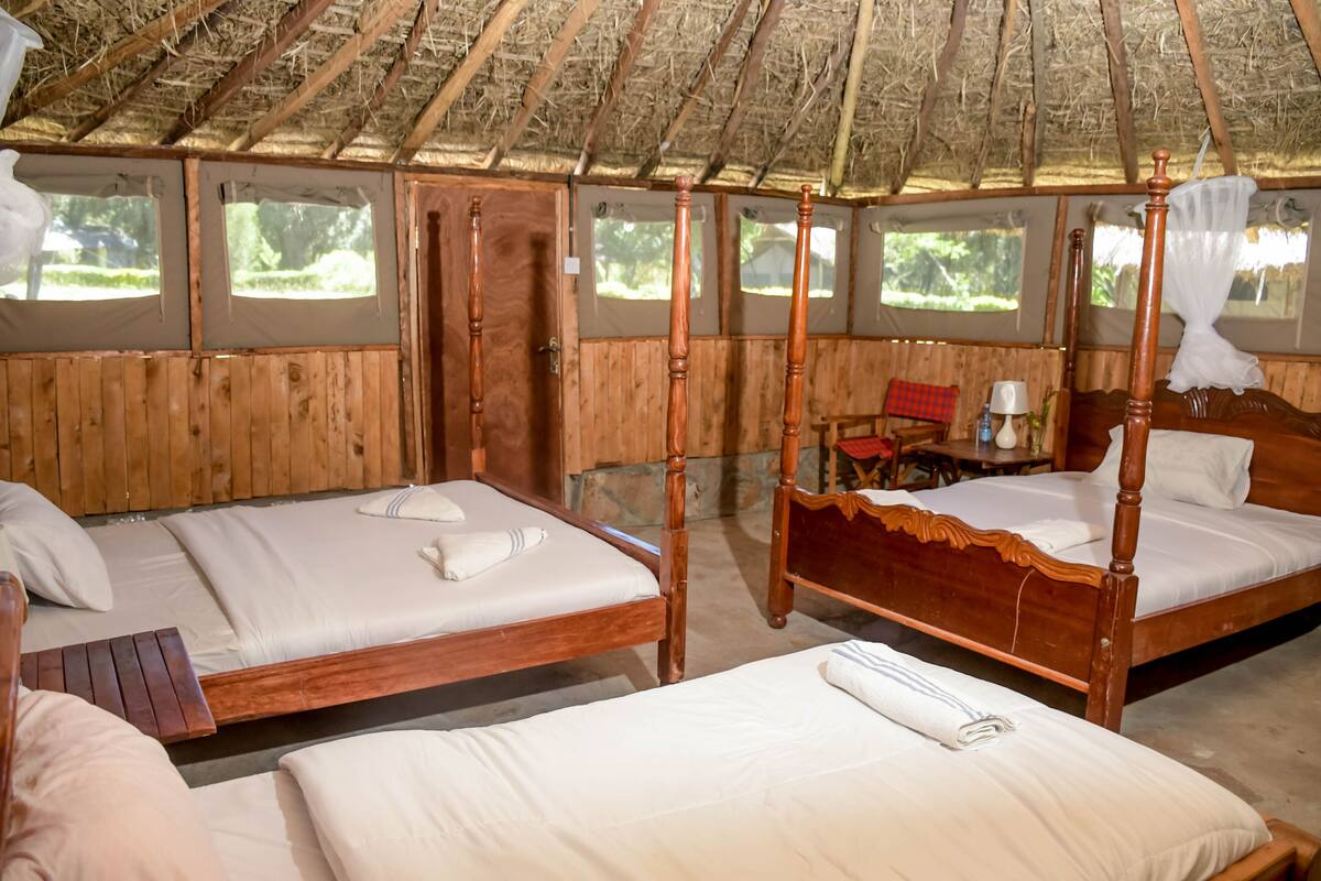 A rustic wooden room with two beds, a wooden bench, and a small table.