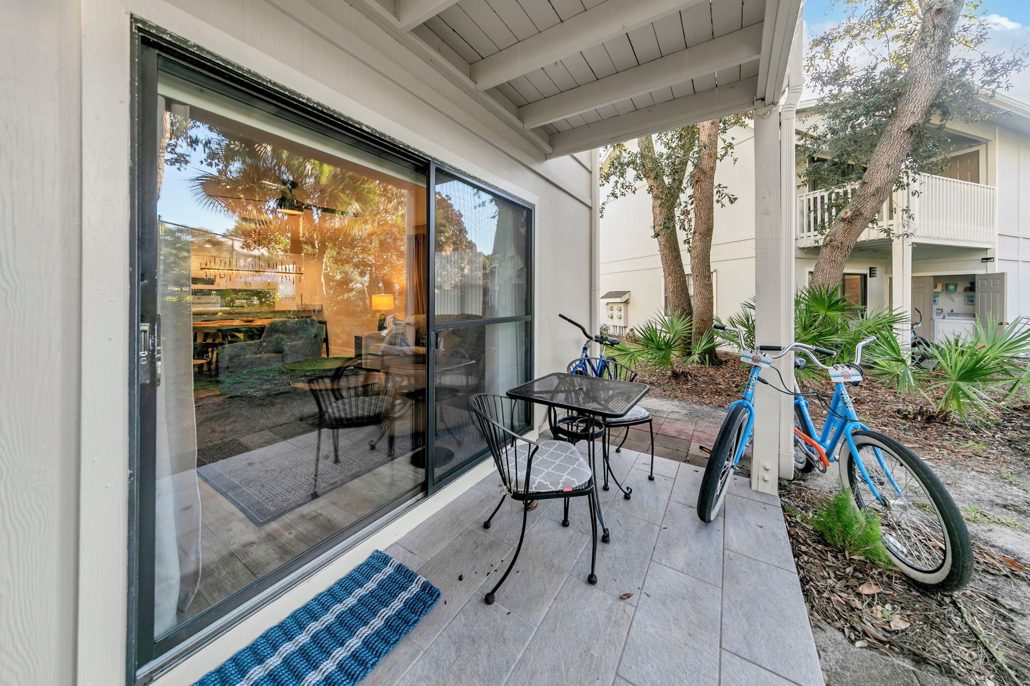 A patio with a table and chairs, a bicycle, and a glass door leading to an outdoor area.