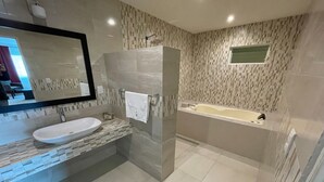Ein modernes Badezimmer mit großem Spiegel, Waschbecken in Weiß, Duschkabine aus Glas und einer Badewanne.