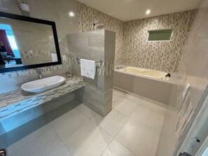 Ein modernes Badezimmer mit großem Spiegel, Waschbecken in Weiß, Duschkabine aus Glas und einer Badewanne.