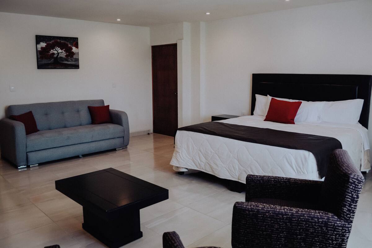 Ein Hotelzimmer mit Bett, Sofa, Couchtisch und einem Gemälde an der Wand.