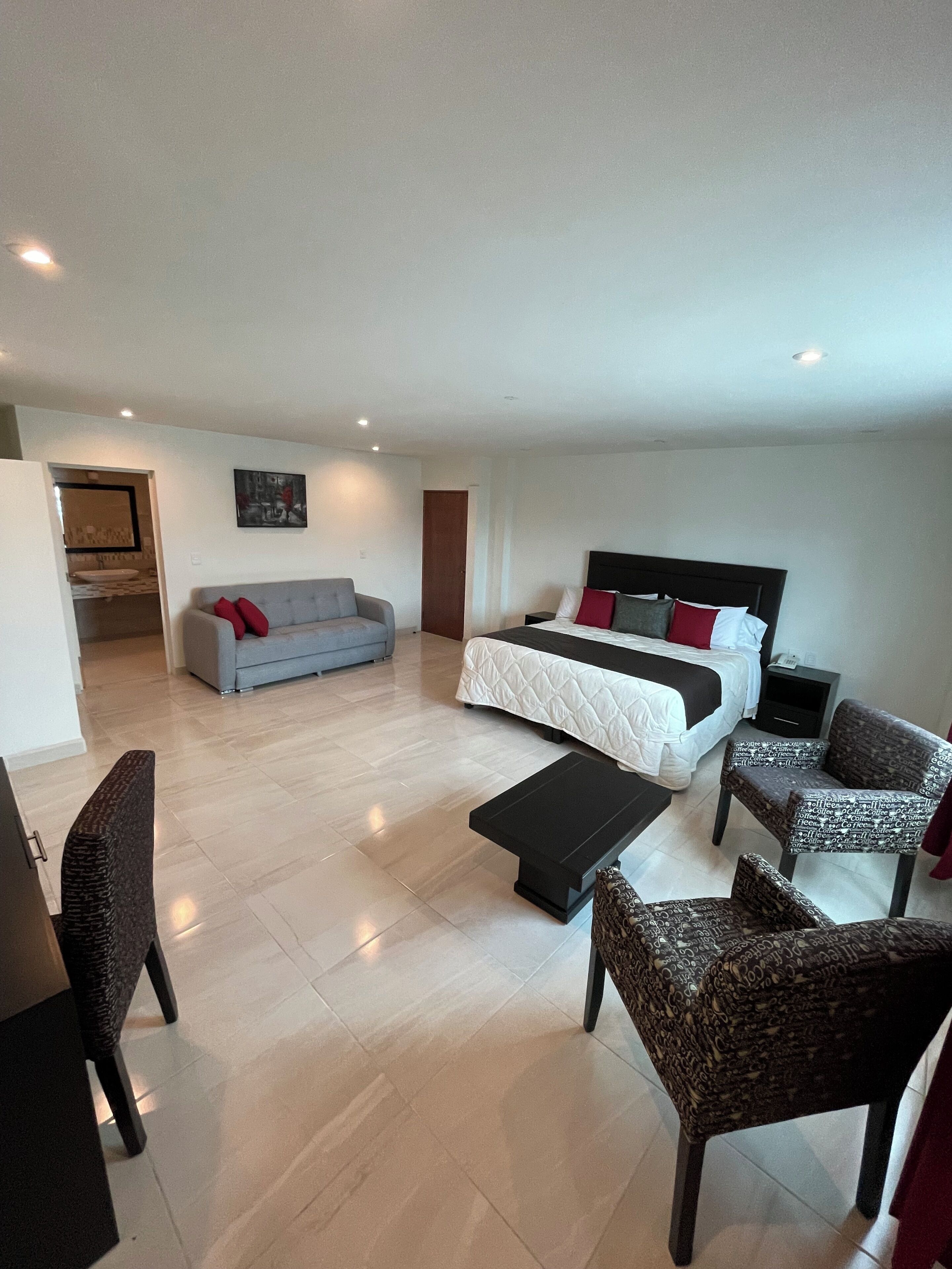 Un dormitorio moderno con una cama grande, un sofá y una mesa de centro.