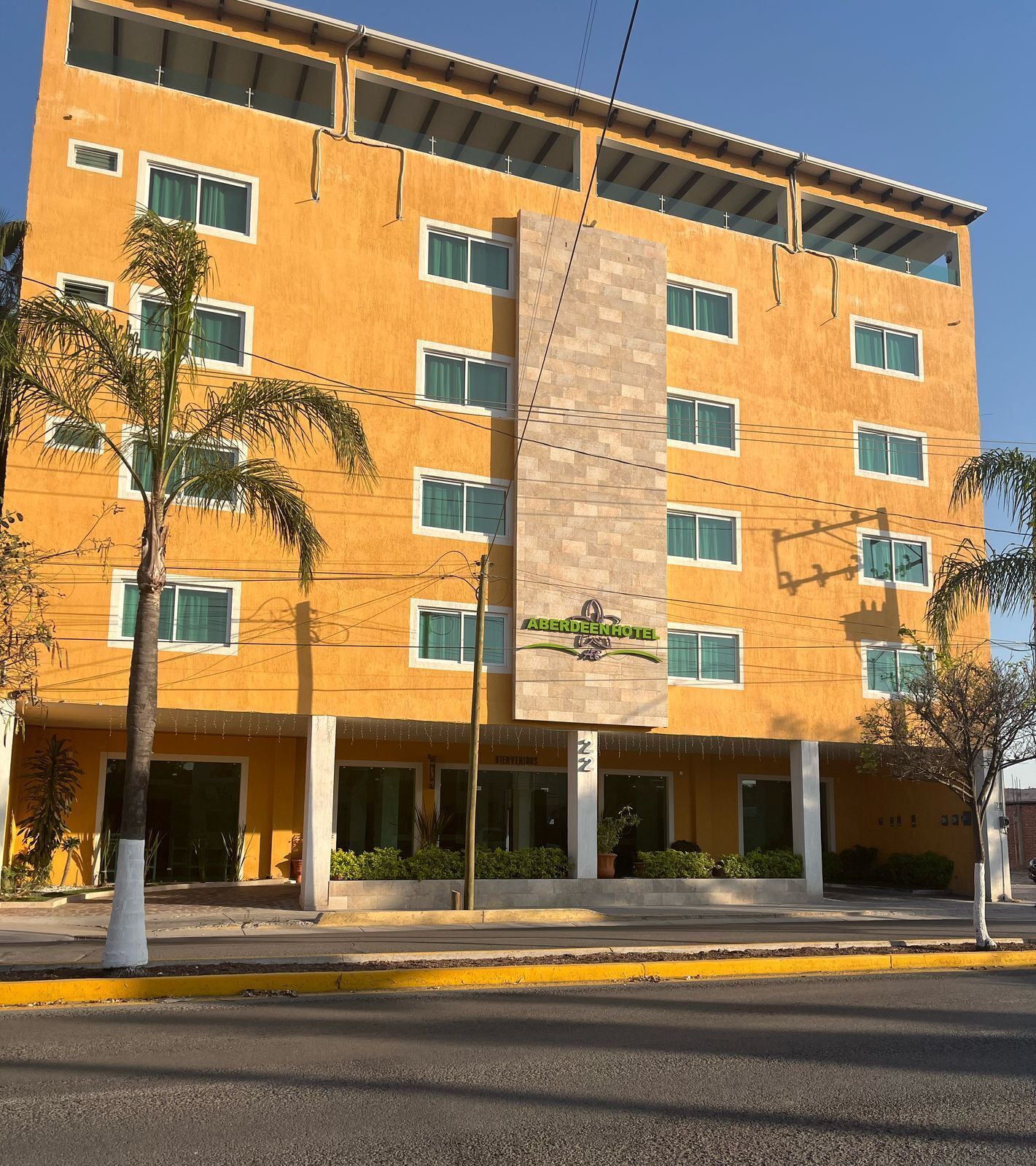 A multi-story hotel with a yellow facade, multiple windows, and a sign for 'ABERDEENHOTEL'.