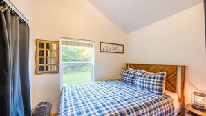 A bedroom with a bed, a window, a wall-mounted picture, and a bedside table with a lamp. - Beaver's Den: Private & Cozy Experience (Beaver)