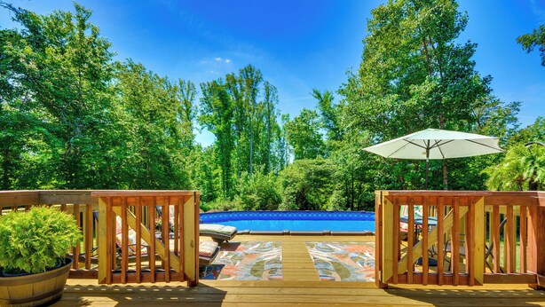 A wooden deck with a pool, surrounded by trees and a view of a blue sky. - Browns Summit Vacation Rental w/ Fire Pit! (Browns Summit)