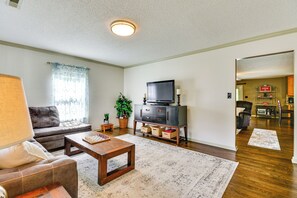 A living room with a sofa, coffee table, TV stand, and a dining area with a table and chairs. - Browns Summit Vacation Rental w/ Fire Pit! (Browns Summit)