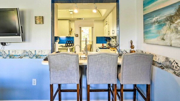 A dining area with a long table, three chairs, and a TV mounted on the wall. - Venice Home w/ Private Pool, 7 Mi to Beach! (Venice)