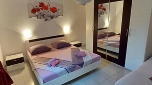 Une chambre à coucher avec un lit, des tables de chevet, une armoire et un miroir.