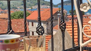 Ein Balkon mit Blick auf rote Ziegeldächer und ein Gewässer.