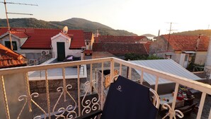 Ein Balkon mit Blick auf Häuser mit roten Dächern und einem Berg im Hintergrund.