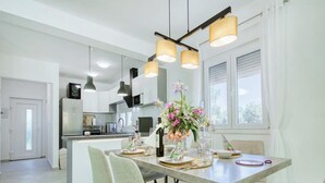 Une cuisine moderne avec des meubles blancs, un îlot central et des luminaires suspendus.