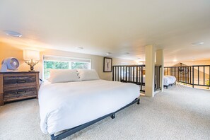A bedroom with a bed, a dresser, a window, a picture frame, and a balcony. - ElkCreekInn: creekside tiny home (Forks)