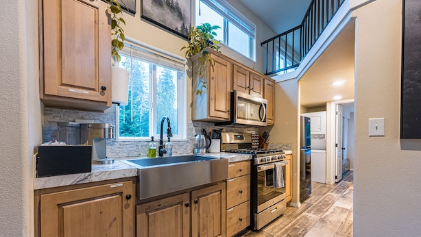 A modern kitchen with wooden cabinets, stainless steel appliances, and a large window.
