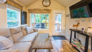 A cozy living room with a sofa, a coffee table, and a TV on a stand.