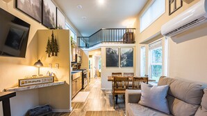 A spacious living area with a sofa, a dining table, and a kitchen with a stove and microwave.