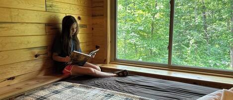 A room with a bed, a window, and a view of trees.