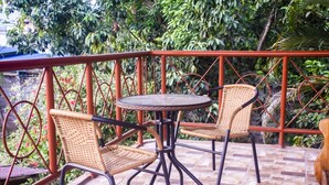 A patio with wicker chairs and a small round table, surrounded by a red metal railing.