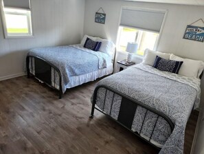 Two single beds with patterned bedspreads are positioned side by side, each with a nightstand in between.